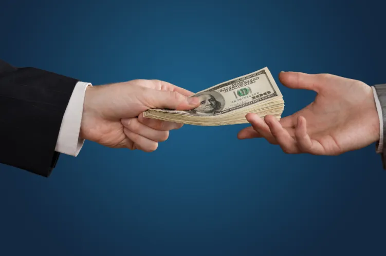 dwie dłonie przekazują sobie pieniądze, dolary 