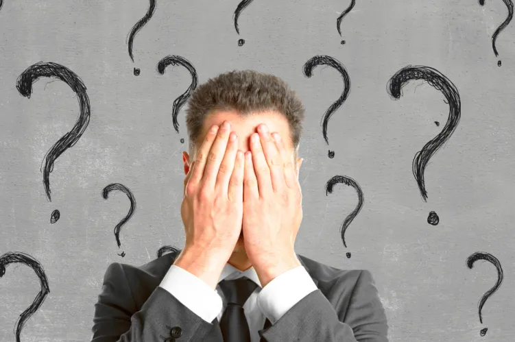 mężczyzna zasłaniający twarz, ze znakami zapytania 