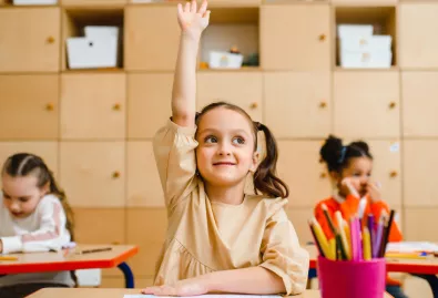 dziewczynka na sali lekcyjnej podnosi rekę